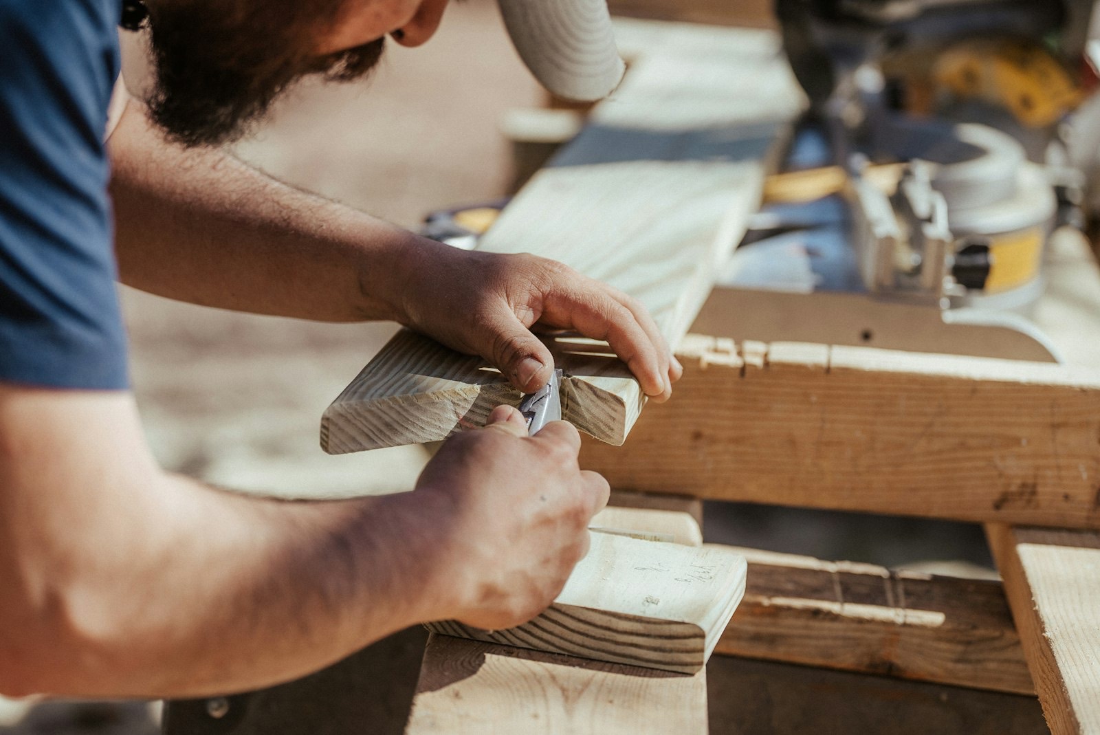 Mains d'un menuisier travaillant une planche de bois (photo d'illustration)