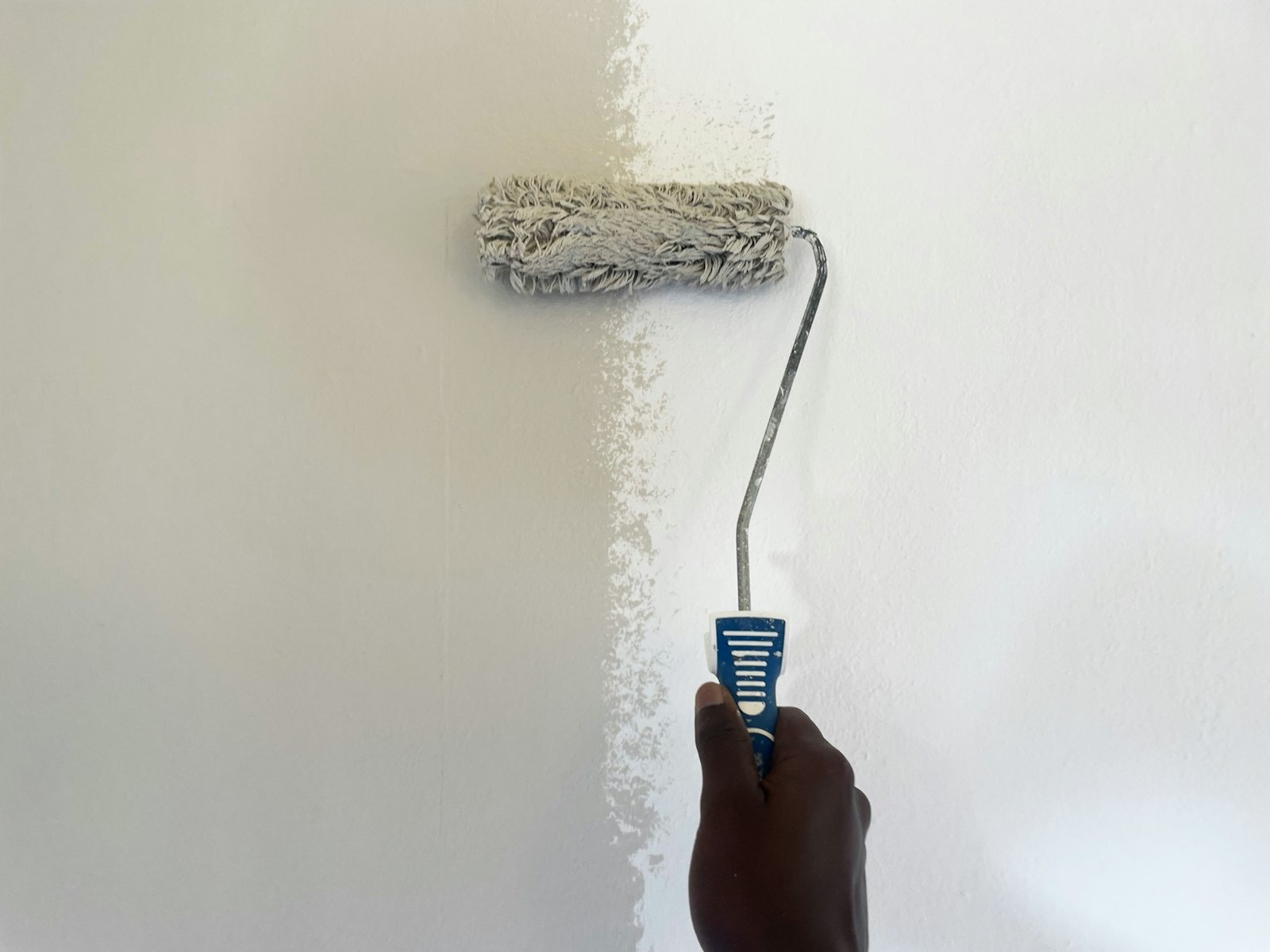 Rouleau de peinture appliquant du blanc sur un mur (photo d'illustration)